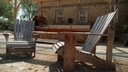 Auf einem Hinterhof stehen zwei handgefertigte Gartenstühle aus Holz. © Screenshot 