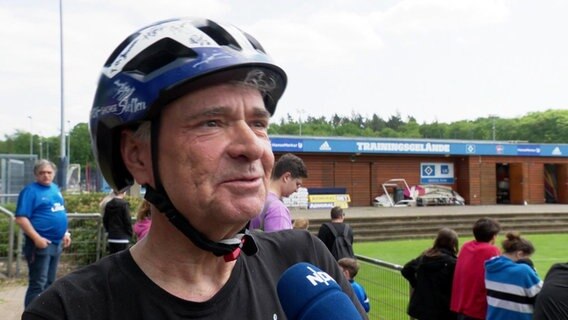 Mann mit Fahrradhelm in HSV-Farben im Interview. © Screenshot 