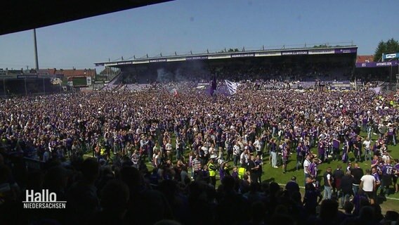 Bei einem Fußballspiel sind nahezu alle Fans auf das Spielfeld gestürmt, um den Sieg ihres Teams zu feiern. © Screenshot 