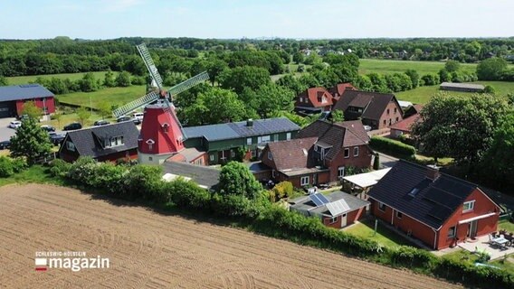 Blick auf Nübbel aus der Luft. Mitten im Ort ragt eine große, rote Windmühle gen Himmel. © Screenshot 