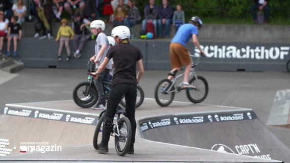 Drei junge Menschen fahren mit ihren BMX-Rädern über die Rampen eines Skateparks. © Screenshot 