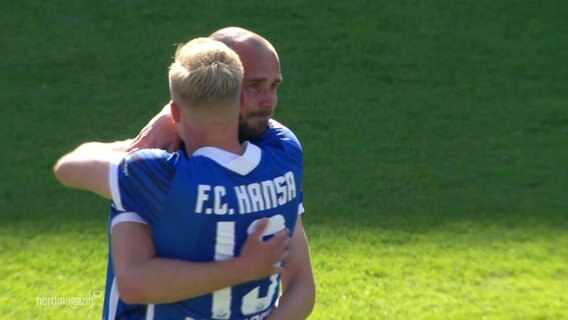 Zwei Spieler des Vereins Hansa Rostock umarmen sich. © Screenshot 