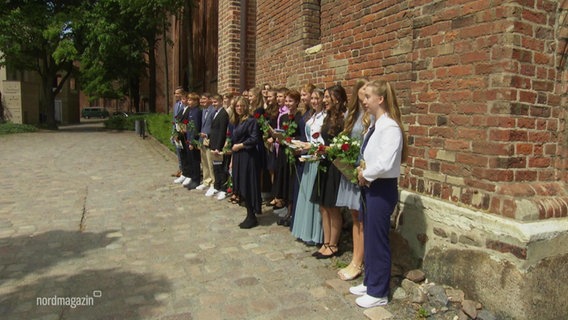 Eine Gruppe von Jugendlichen halten Blumen kurz nach ihrer Konfirmation. © Screenshot 