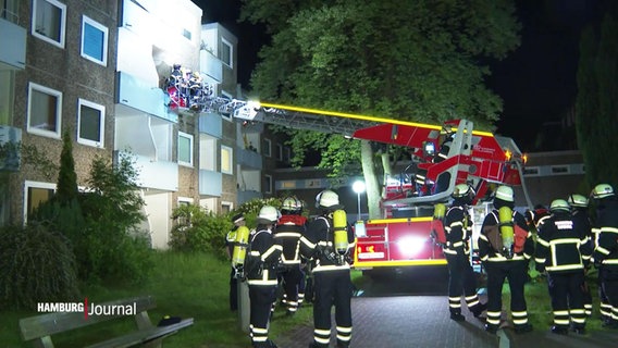 Ein Feuerwehrauto vor einer Wohnanlage. Mit einer Drehleiter versuchen die Feuerwehrleute auf den Balkon einer Wohnung zu kommen, in der es brennen soll. © Screenshot 