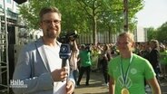 Reporter Matthias Zimmermann schaut lächelnd in die Kamera. Neben ihm steht VfL-Wolfsburg-Spielerin Alexandra Popp. © Screenshot 