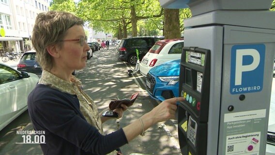 Eine Frau kauft eine Parkticket an einem Automaten. © Screenshot 