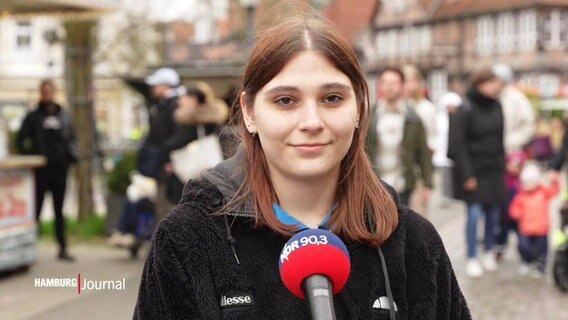 Ein Mädchen steh bei einer Straßenumfrage vor einem Mikrofon von NDR 90,3. © Screenshot 