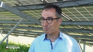 Bundeslandwirtschaftsminister Cem Özdemir (Grüne) steht bei einem Interview unter einer Solaranlage. © Screenshot 