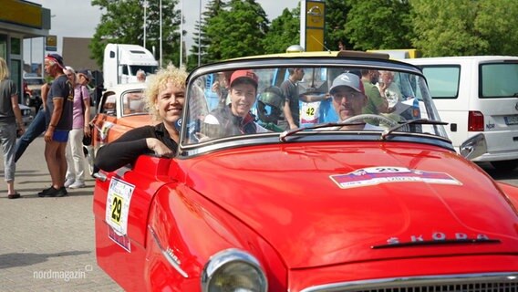 Menschen sitzen in einem roten Oldtimer Cabrio. © Screenshot 