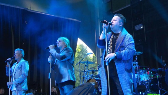 Die Sänger der Band "Die Prinzen" singen bei einem Auftritt leidenschaftlich in Standmikrofone. © Screenshot 