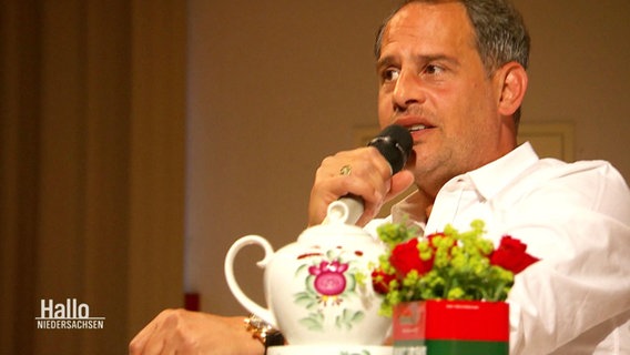 Moritz Bleibtreu sitzt vor einer Kanne Tee und spricht in ein Mikrofon. © Screenshot 