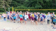 Viele Kinder stehen auf einem Beach Volleyball Feld. © Screenshot 