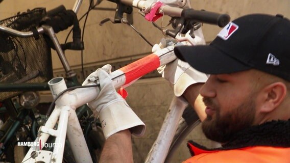 Ein Mitarbeiter der Stadtreinigung lädt ein Schrottfahrrad in einen LKW. © Screenshot 