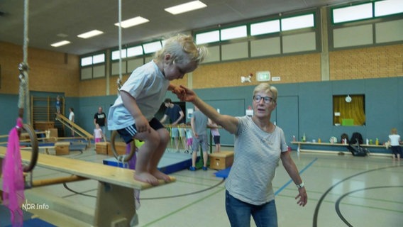 Ein Kind und eine Übungsleiterin beim Turnen. © Screenshot 