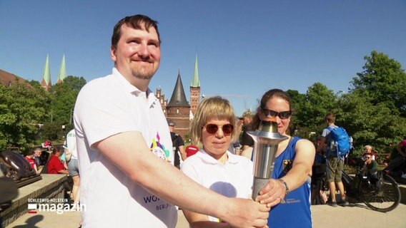 Teilnehmende der Special Olympics halten die Flame der Hoffnung beim Fackellauf in Lübeck. © Screenshot 