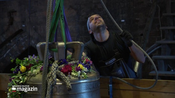 Ein Handwerker zieht die Glocke der Marienkirche in Lübeck hoch. © Screenshot 