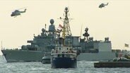 Ein Kriegsschiff und mehrere kleine (zivile) Boote tümmeln sich auf einem Gewässer. © Screenshot 