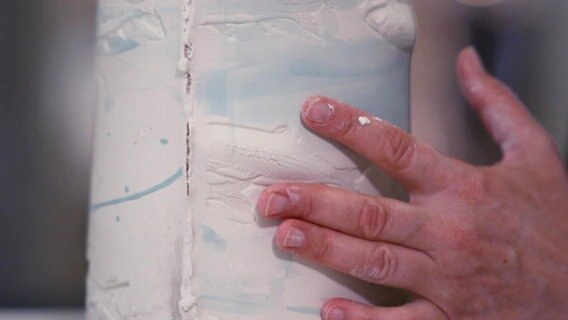 Eine Person formt porzellan mit ihren Händen. Heringe sind darin eingeritzt. © Screenshot 