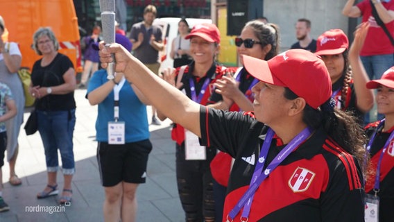 Eine Athletin der peruanischen Special-Olympics Delegation hält das olympische Feuer in die Luft. © Screenshot 