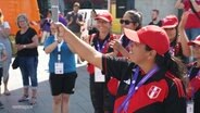 Eine Athletin der peruanischen Special-Olympics Delegation hält das olympische Feuer in die Luft. © Screenshot 