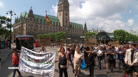 Viele Menschen mit Transparenten gehen in einem Demozug am Hamburger Rathausplatz vorbei. © Screenshot 