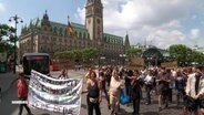 Viele Menschen mit Transparenten gehen in einem Demozug am Hamburger Rathausplatz vorbei. © Screenshot 