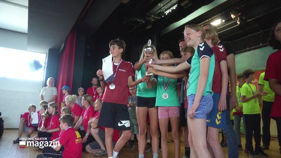 Mehrere Kinder und Jugendliche halten gemeinsam einen Pokal und eine Urkunde. © Screenshot 