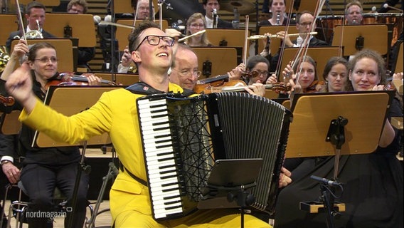 Ein Akkordeonspieler performt zusammen mit einem Orchester. © Screenshot 