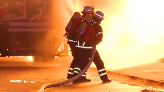 Feuerwehrmenschen mit Schlauch vor lodernden Flammen © Screenshot 