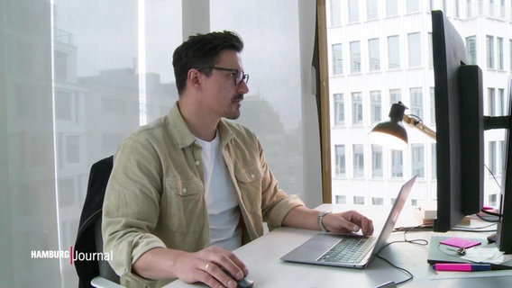 Person mit Brille aneinem Schreibtisch mit zwei Computern © Screenshot 