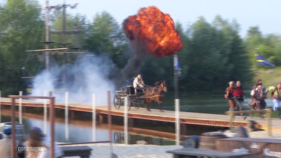 Eine Szene aus einem Action-Theaterstück: Im Hintergrund eine Explosion. © Screenshot 