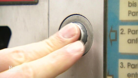 Zwei Finger drücken auf einen Parkscheinautomatenknopf. © Screenshot 