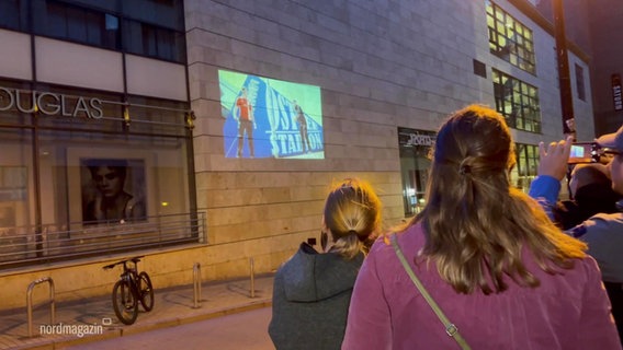 Zuschauer beim betrachten eines Films, der auf eine Hauswand projeziert wird. © Screenshot 
