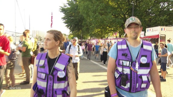 Zwei Personen des "Awareness-Teams" auf der Kieler Woche, erkennbar an lilanen Westen. © Screenshot 