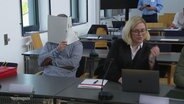Der Angeklagte hinter einem Schnellhefter im Gerichtssaal. © Screenshot 