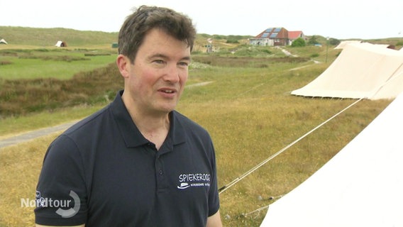 Thorsten Kaiser im Interview, im Hintergrund stehen Zelte. © Screenshot 