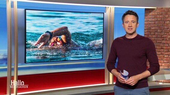 Moderator Jan Starkebaum, im Hintergrund ein Bild einer schwimmenden Person. © Screenshot 