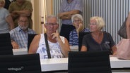 In den Sitzreihen der Abgeordneten des Schweriner Landtags sitzen Bürgerinnen und Bürger beim Tag der offenen Tür. © Screenshot 