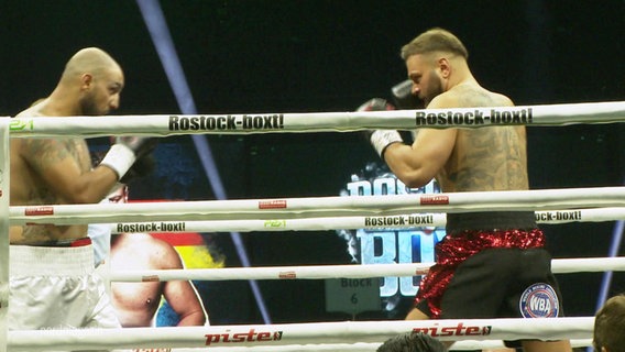 Zwei Boxer stehen mit erhobenen Fäusten sich gegenüber bei einem Kamp in einem Ring. © Screenshot 