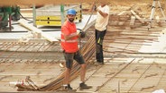 Zwei Bauarbeiter auf einer Baustelle. © Screenshot 