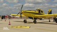 Ein Löschflugzeug der Feuerwehr steht in gelb, blauer Farbe auf dem Rollfeld. © Screenshot 