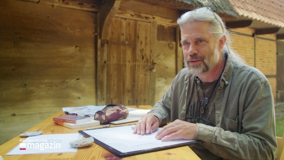 Der Geologe Johannes Jansen mit Papier und Stiften an einem Tisch. © Screenshot 