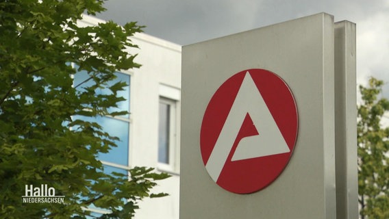 Vor einem Bürogebäude steht ein Schild mit dem Logo der Agentur für Arbeit. © Screenshot 