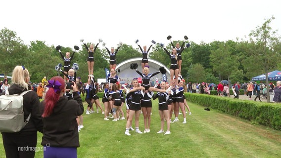 Cheerleader präsentieren sich mit Figuren. © Screenshot 