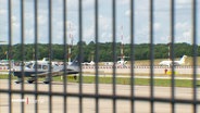 Durch einen Zaun erkennt man einen Flughafen mit Privatjets. © Screenshot 