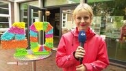 Julia Wulf steht vor einer 40. © Screenshot 