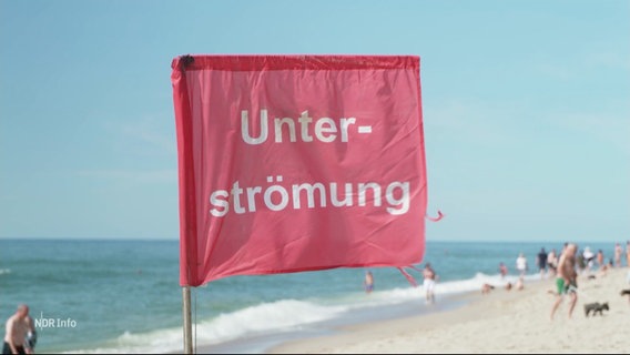 Eine rote Flagge an einem Strand warnt vor Unterströmungen. © Screenshot 