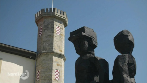 Eine moderne Skulpur im Vordergrund, im Hintergrund ein Turm von Schloss Derneburg. © Screenshot 
