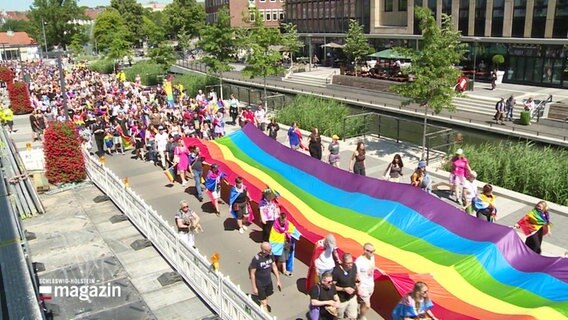 Kiel beim CSD 2023: Menschen tragen eine riesige Regenbogenflagge durch die Innenstadt. © Screenshot 