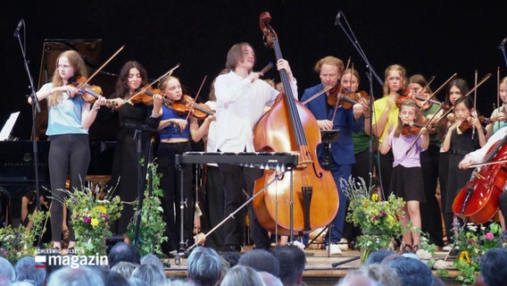 Kinder mit Geigen auf einer Bühne. © Screenshot 